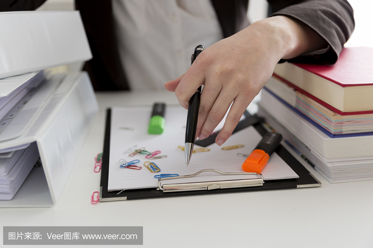 坐在滿是文書(shū),書(shū)籍和文件的桌子旁的女人。混亂的工作場(chǎng)所。過(guò)載和過(guò)度勞累